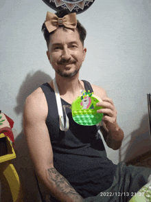 a man wearing a bow on his head is holding a green pop it toy
