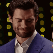 a man with a beard is wearing a blue suit and a white shirt .
