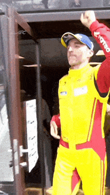 a man in a yellow and red racing suit is standing in front of a door