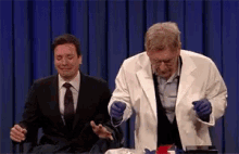 jimmy fallon and a man in a lab coat are on a stage