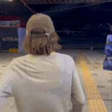 a person wearing a hat and a white shirt is walking down the street