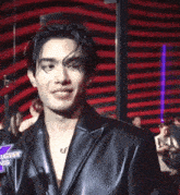 a man in a black leather jacket is smiling and looking at the camera