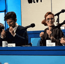 a man and a woman sit at a table with a sign that says john turturro on it