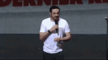 a man is standing on a stage holding a microphone and talking into it .