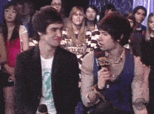 two men are talking into microphones in front of a crowd