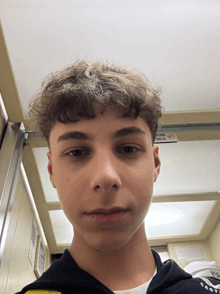 a young man in an elevator with a no smoking sign above him