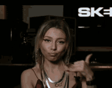 a woman is giving the middle finger in front of a sign that says sky