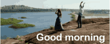 a man and a woman standing on top of a rock near a body of water with the words good morning