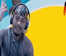 a man wearing headphones and a bandana on his head is giving a peace sign .