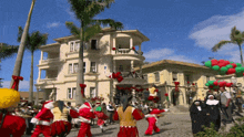 a group of people dressed as santa claus are walking in front of a large house