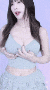 a woman in a crop top and ruffled skirt is adjusting her breasts .