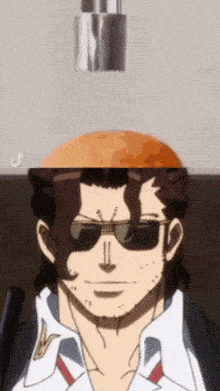 a man wearing sunglasses and a white shirt has a large orange on his head .