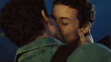 two young men are kissing each other on the cheek .