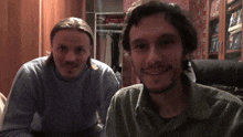 two men are posing for a picture and one of them is wearing a blue sweater