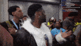 a man in a white fur coat stands in a crowd of people with a hashtag that starts with the letter r