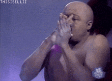 a man without a shirt is blowing a star with his hands