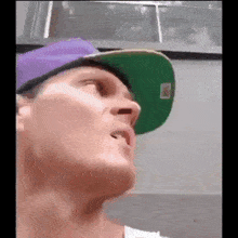 a man wearing a purple hat and a green hat is looking up .
