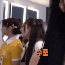 a group of girls are standing in front of a mirror with chinese writing on the wall behind them
