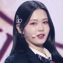 a close up of a woman wearing a microphone and a butterfly hair clip