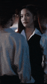 a woman is holding a baby in her arms in a dark room while another woman looks on .