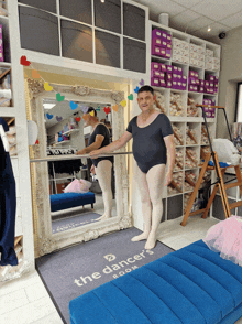 a man in a leotard is standing in front of a mirror in a room that says the dancer 's room