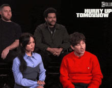 a group of people are sitting in front of a black background that says hurry up tomorrow