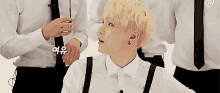 a man in a white shirt and suspenders is sitting in front of a group of men .