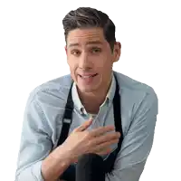 a man wearing a blue shirt and black suspenders stands in front of a black microphone