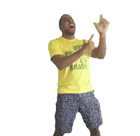 a man wearing a yellow shirt that says brasil is holding something in his hands