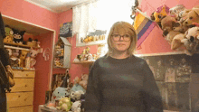 a girl in a room with stuffed animals and a poster of a band