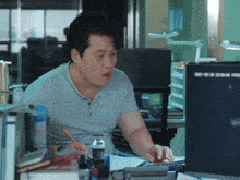 a man sitting at a desk with a bottle of water and a pencil in his hand