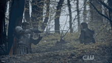 a man in armor is holding a sword in a forest with the letters cw on the bottom right