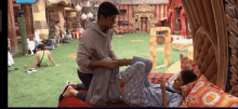 a man kneeling next to a woman laying on a bed in a room with a sign that says channel 1