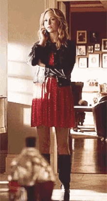 a woman in a red dress and black boots talking on a cell phone