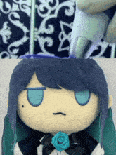 a close up of a stuffed doll with a blue rose in her mouth
