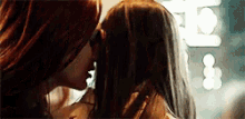 two women are kissing each other in front of a crowd .