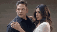 a man and a woman are standing next to each other and the woman is wearing a diamond ring