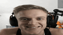 a man wearing headphones and a blue microphone smiles for the camera