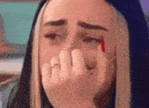 a woman with red nails is crying while covering her face with her hands .