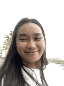 a woman with long hair and a white shirt smiles for the camera