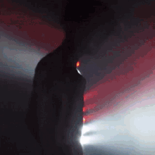 a silhouette of a man in a dark room with red and white lights