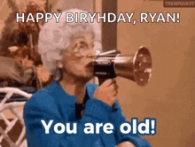 an elderly woman is blowing into a megaphone and saying `` happy birthday ryan ! you are old ! ''