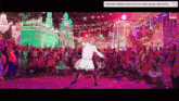 a man in a white robe is dancing in front of a crowd in a video