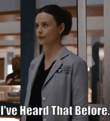 a woman in a lab coat is standing in front of a window and says " i 've heard that before "