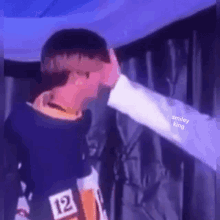 a man is touching another man 's face while standing next to each other .