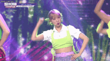 a woman in a neon green crop top is dancing on a stage