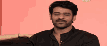 a man in a black shirt is making a funny face with his hands
