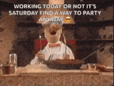 a man in a chef 's hat is sitting at a table with a pan of food .
