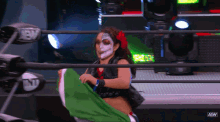 a woman in a wrestling ring holding a green and white flag that says aew on it