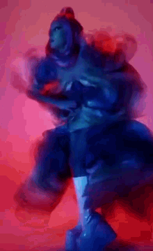 a blurry picture of a woman in a blue dress dancing on a red background .